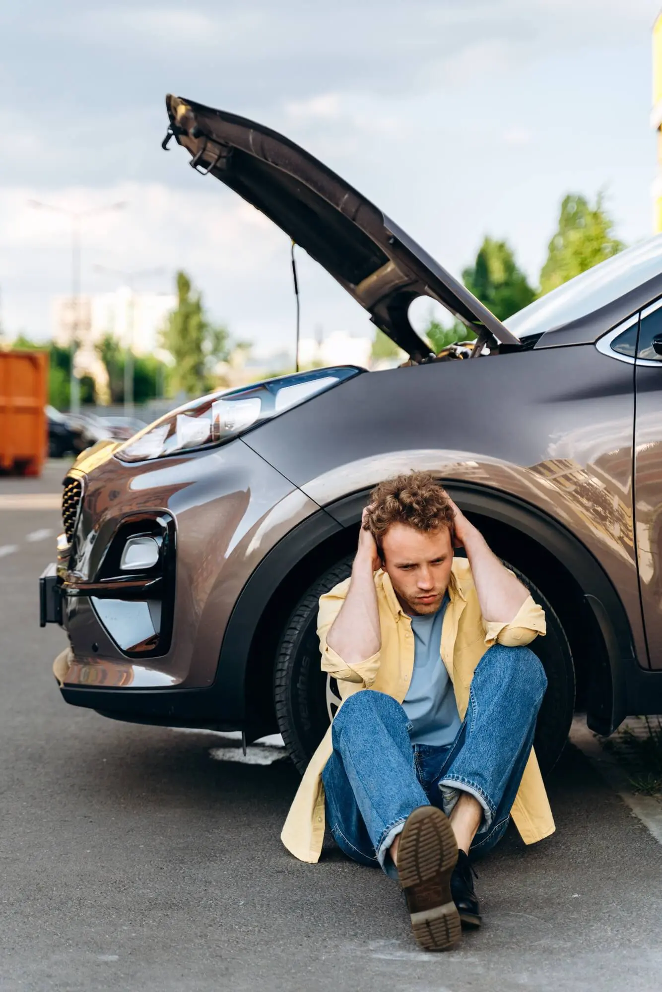 Driver standing by his car with the bonnet open after a breakdown