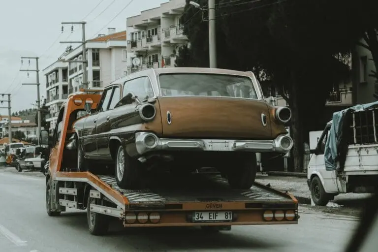 Classic car transport on a flatbed recovery truck with all four wheels off the ground