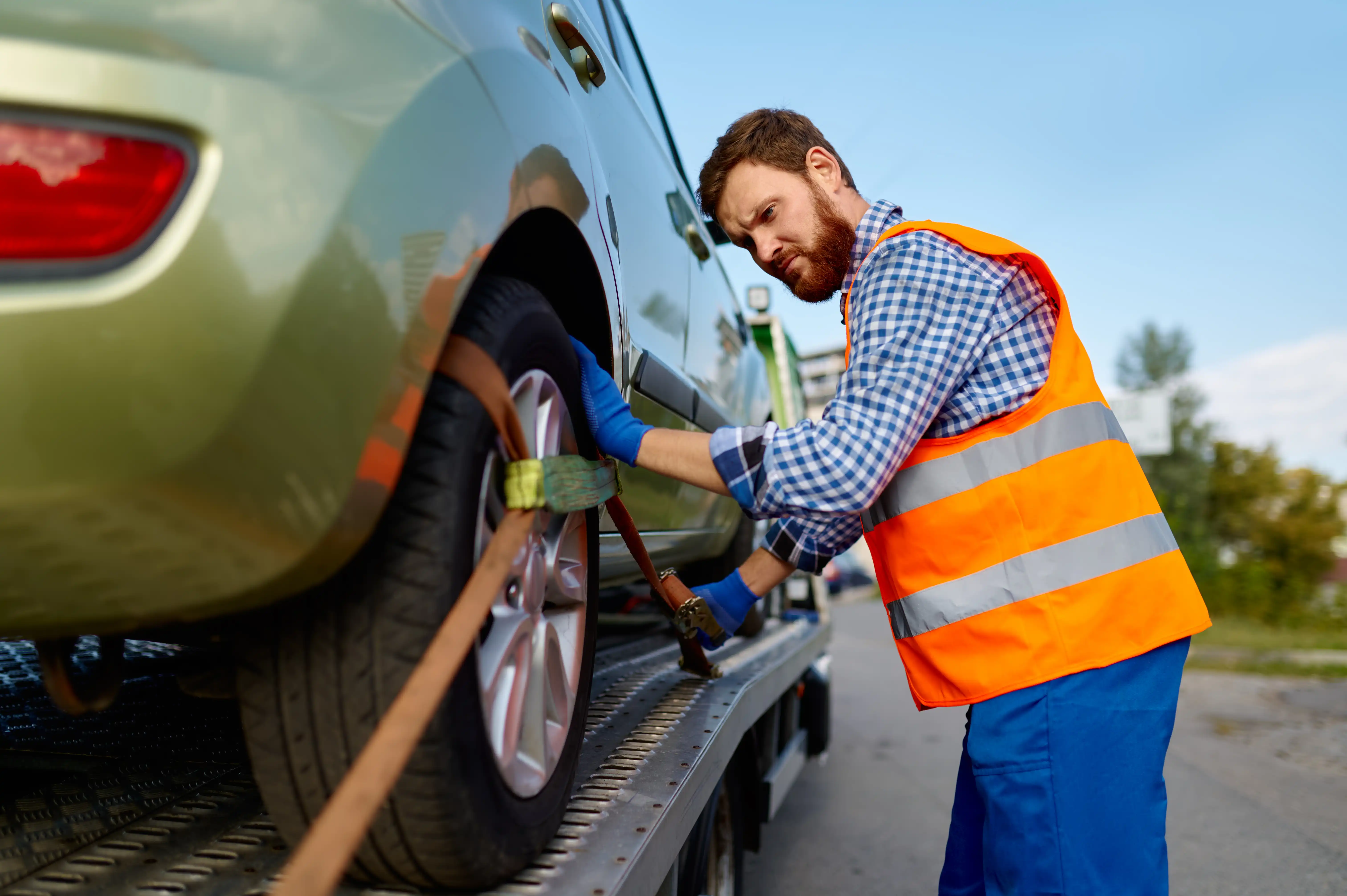 Recovery driver securing vehicle straps on the flatbed truck