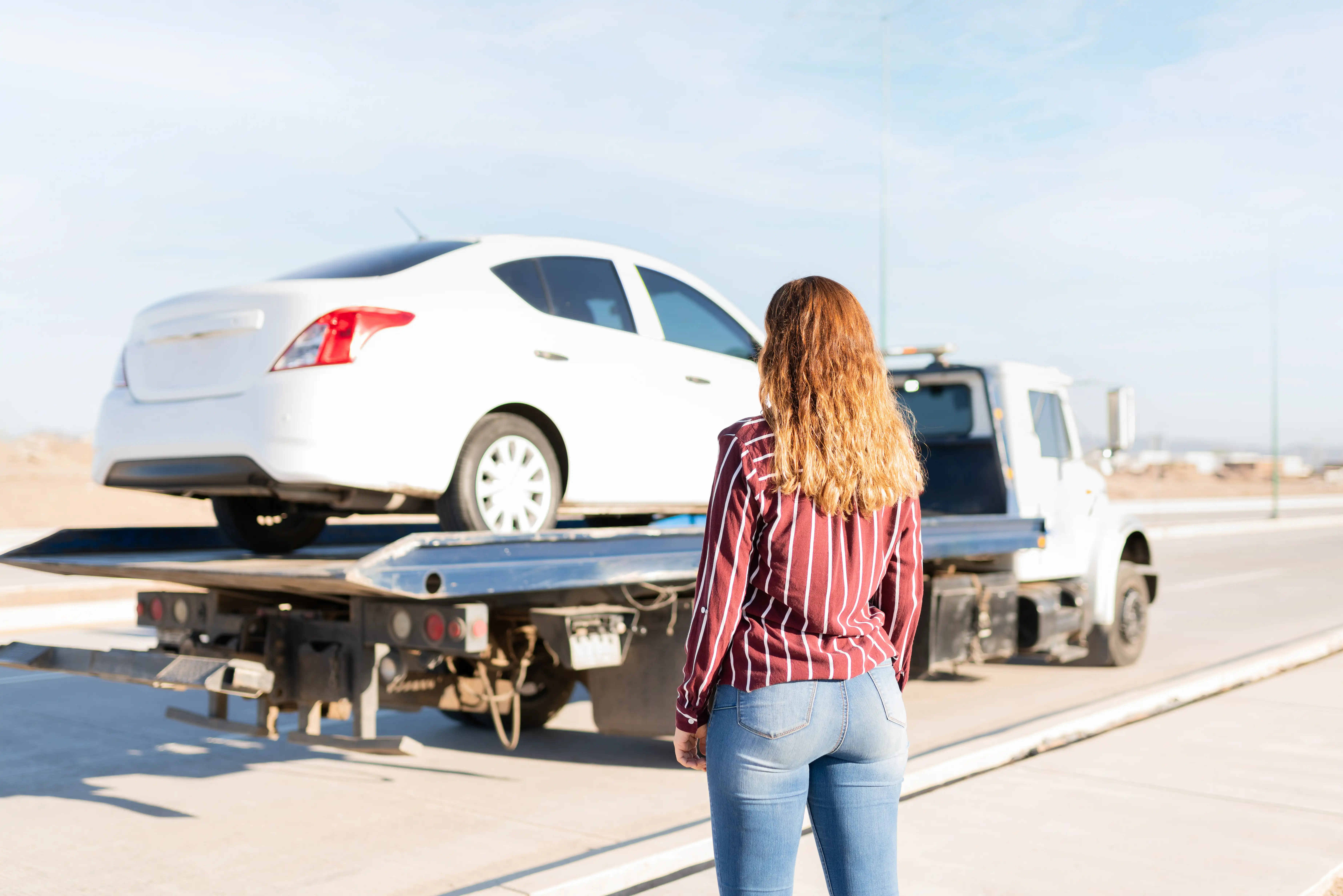 Customer standing with their vehicle safely loaded on a Fast Track Recovery flatbed